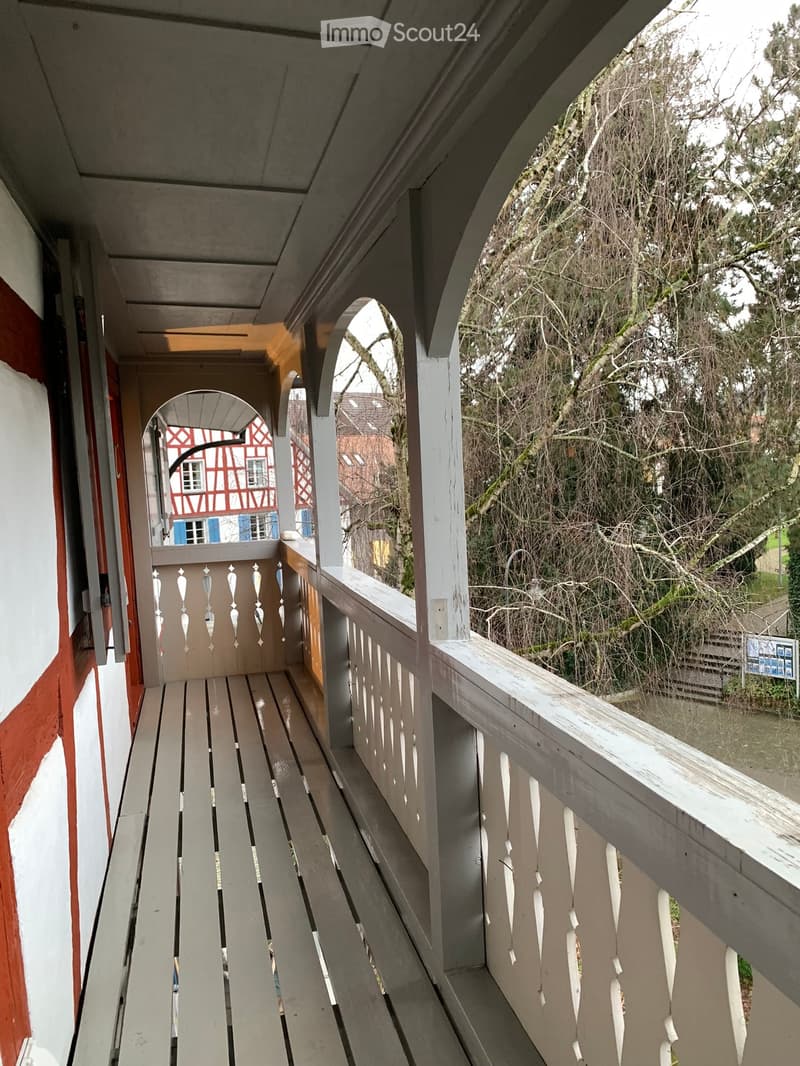 {"visible_features": ["Balcony / Terrace"],"type": "Balcony","description": "Wooden balcony with arched windows, overlooking a forested area"}