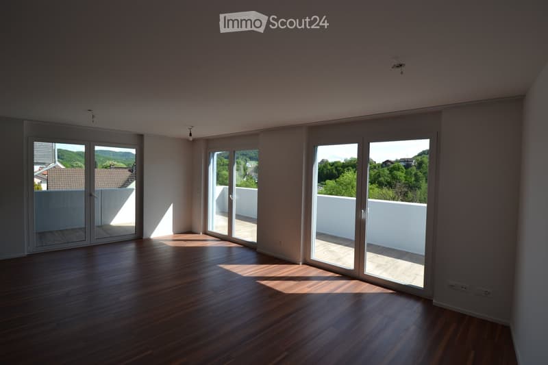 Empty room with wooden flooring, large sliding glass doors leading to a balcony, and natural light streaming in.