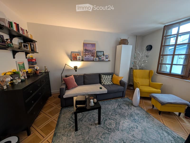Living room with grey sofa, yellow armchair, coffee table, and a blue rug on wooden flooring.