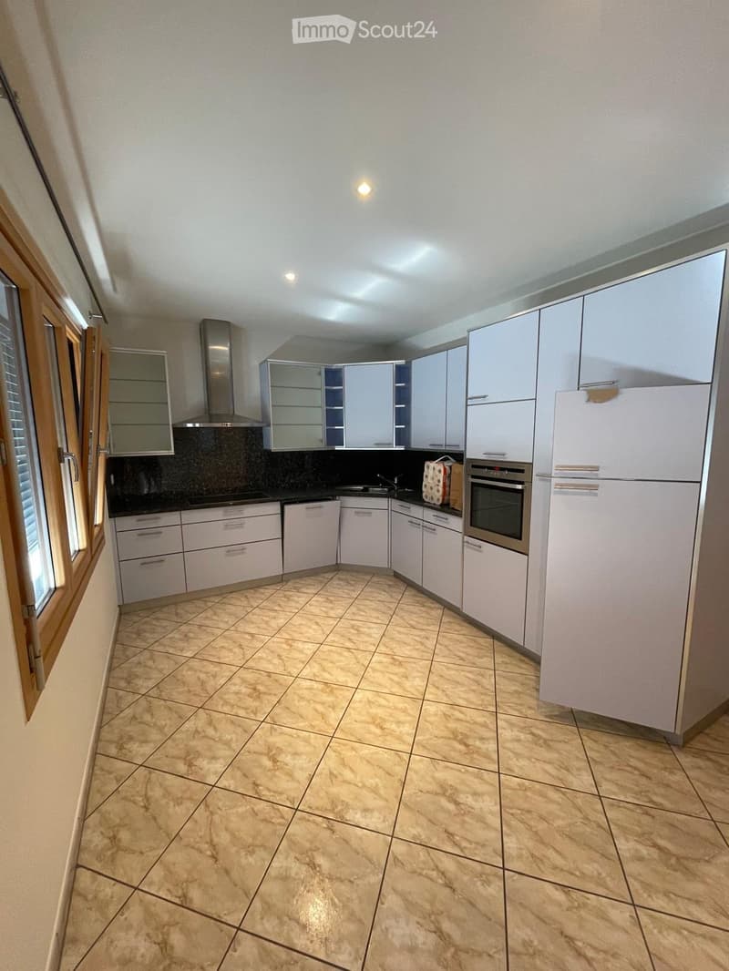 Modern kitchen with white cabinets, stainless steel appliances, tiled floor, and a window with blinds.