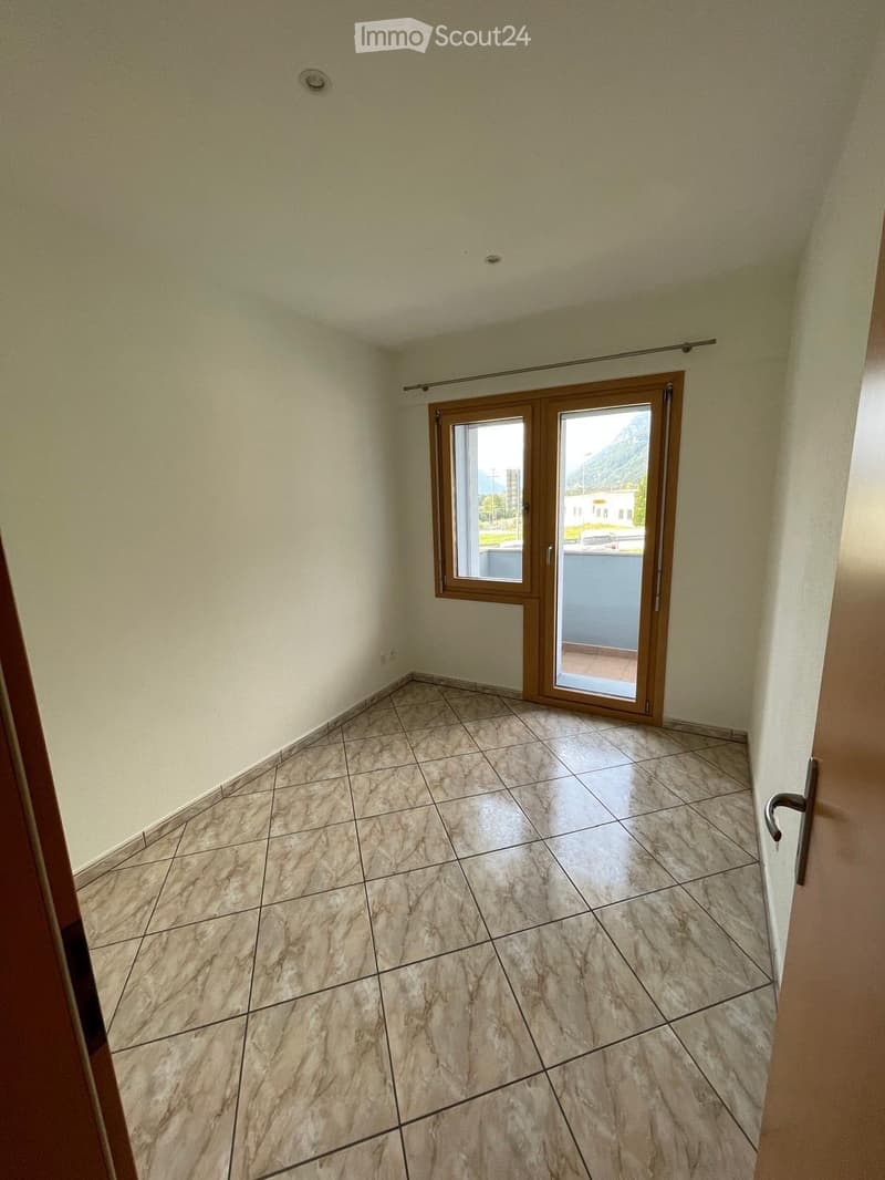 Empty room with tiled floor and large sliding glass door leading to a balcony.