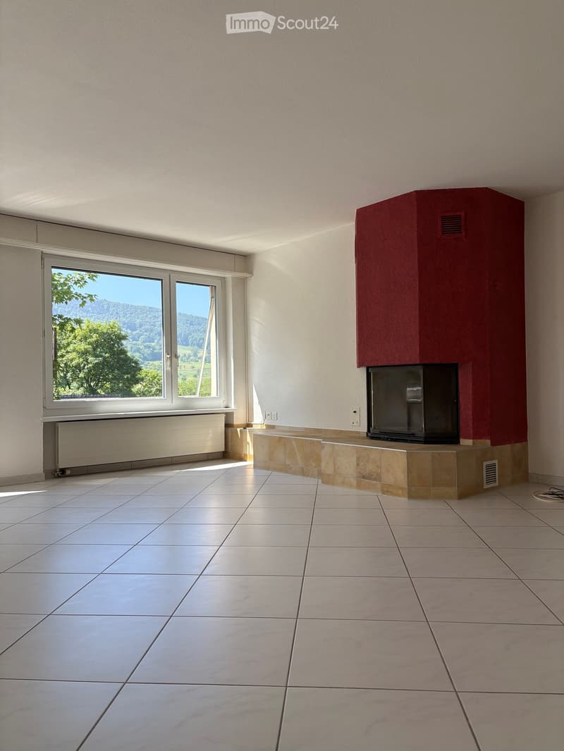 Empty room with tiled floor, fireplace, large window with scenic view, radiator, and power outlets.