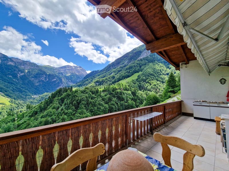 Balcony with wooden railing, tiled floor, and scenic mountain view.