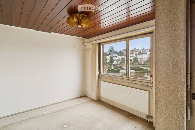 empty room, white walls, wooden ceiling, large window with city view