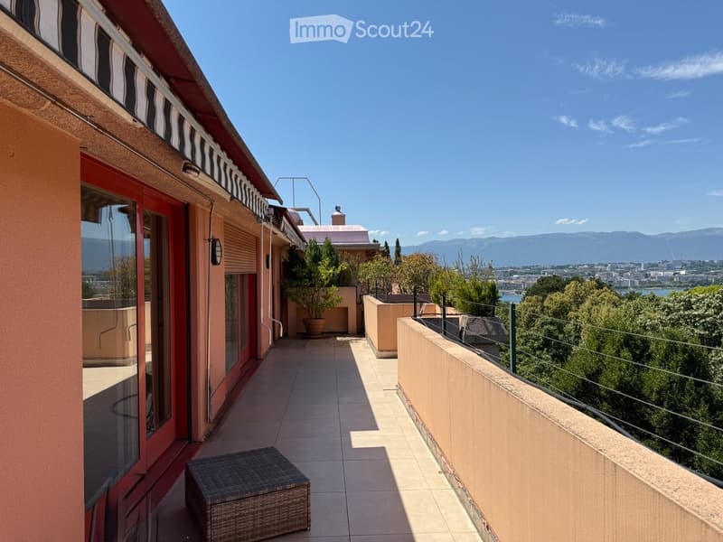 Balcony with tiled floor, wicker chair, potted plants, and scenic city and mountain views.