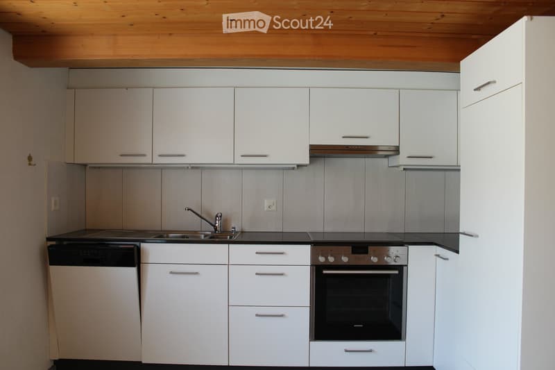 Modern kitchen with white cabinets, stainless steel appliances, and a black countertop.