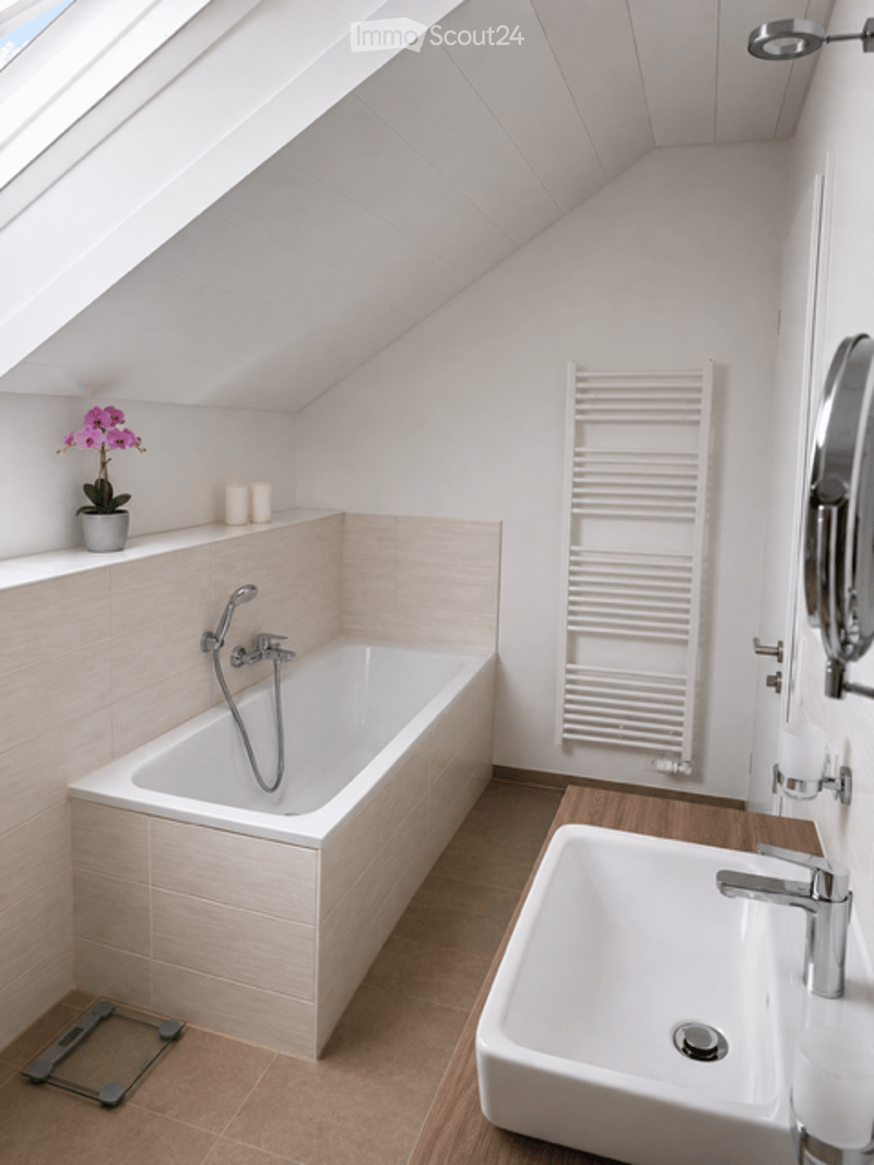 Modern bathroom with a bathtub, sink, mirror, radiator, and decorative elements like a flower and candles.