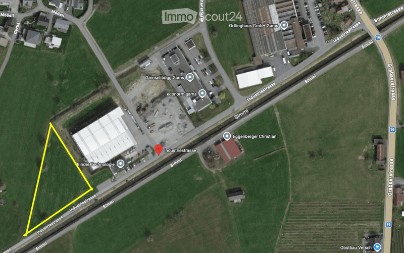 Aerial view of an area with fields, roads, buildings, and a marked plot of land.