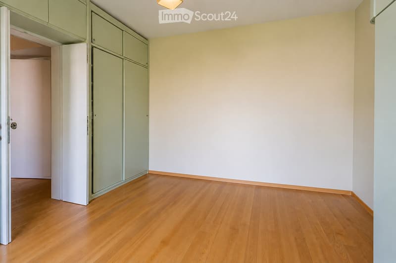 Empty room with light-colored walls, wooden flooring, and built-in closet units.
