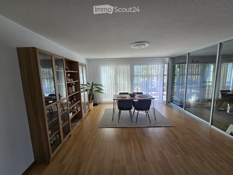 Modern dining area with wooden floor, large glass sliding doors, and a sleek dining table with chairs.