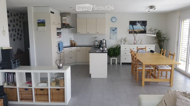 Bright, modern kitchen with white cabinets, a central island, a dining table with chairs, and various appliances and decorative items.