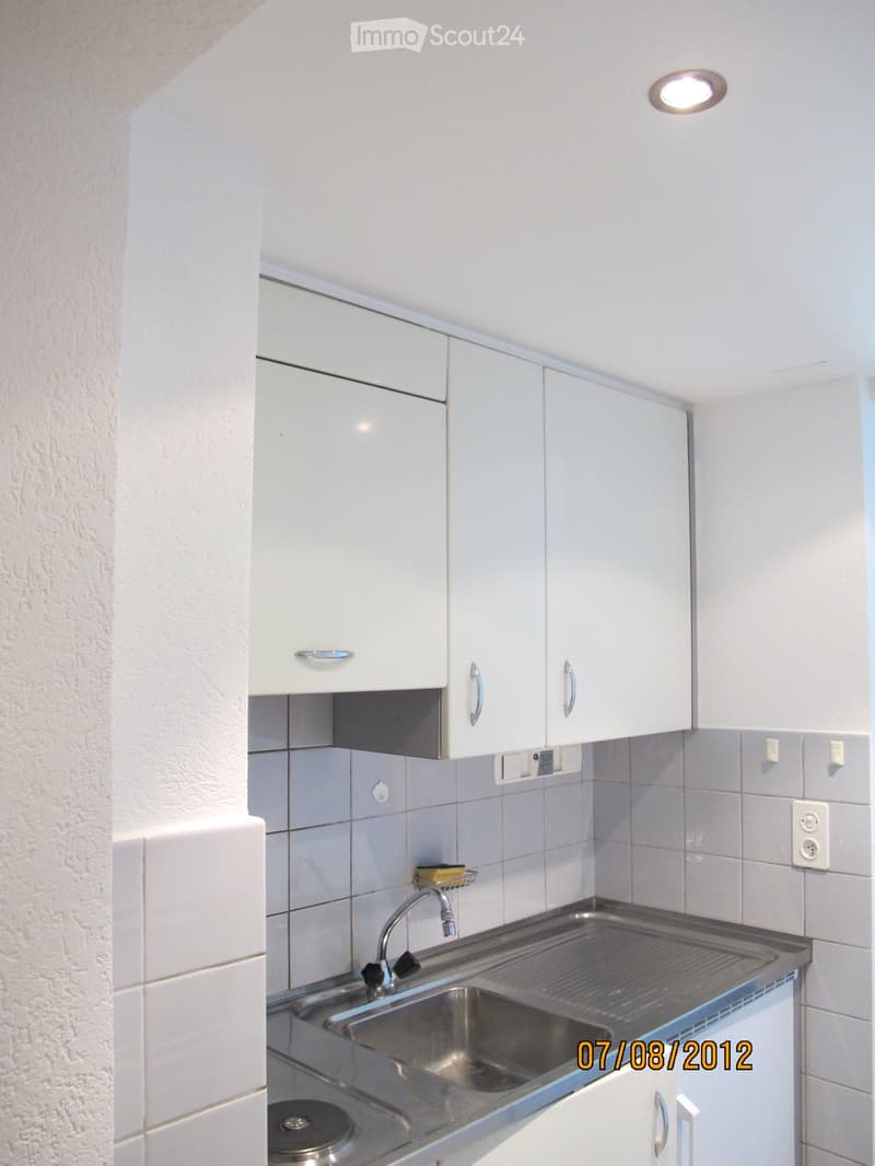 Modern kitchen with white cabinets, stainless steel sink, and tiled backsplash.