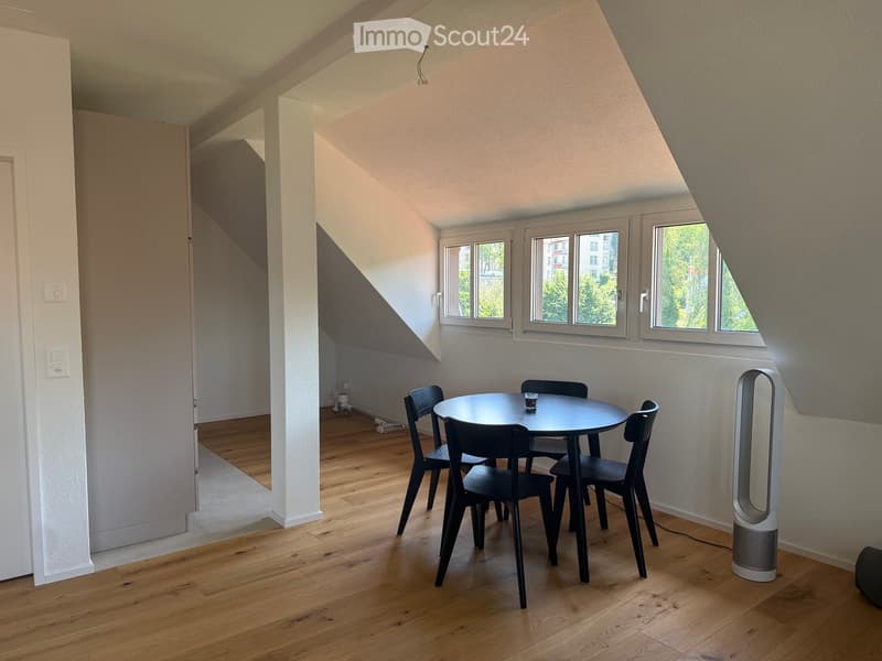 Bright, modern room with wooden flooring, large windows, a round dining table with four chairs, and an air purifier in the corner.