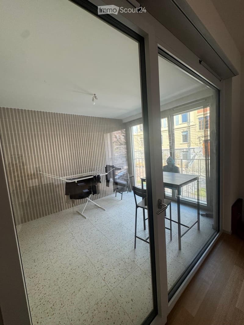 Balcony with a table and chairs, clothes drying rack, and a view of the city.
