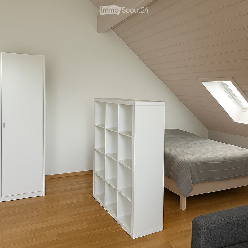 Modern bedroom with wooden flooring, slanted wooden ceiling, white walls, bed with grey bedding, white wardrobe, white shelving unit, and grey sofa.