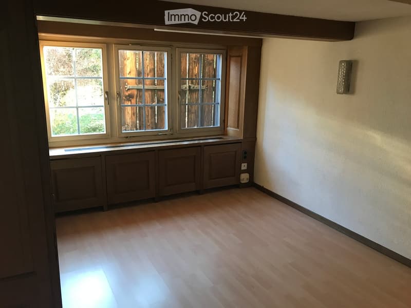 Empty room with wooden flooring, large windows, and built-in cabinets below the windows.