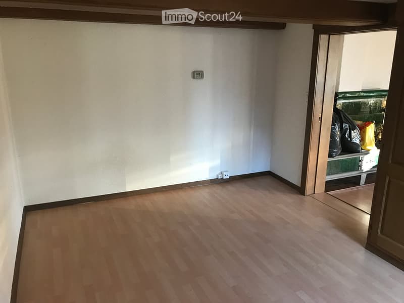 Empty room with light wooden flooring and white walls, featuring a partially open door leading to an outdoor area.