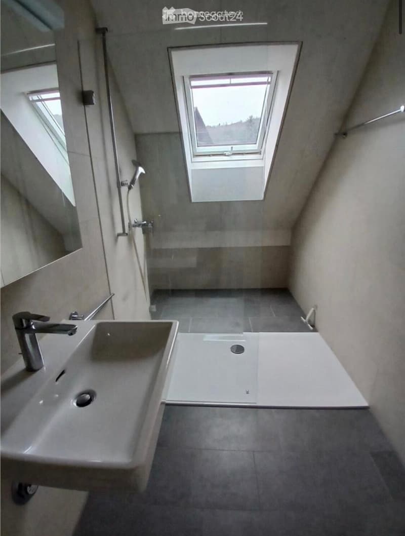 Modern bathroom with a large sink, bathtub, and a skylight window above the bathtub area.