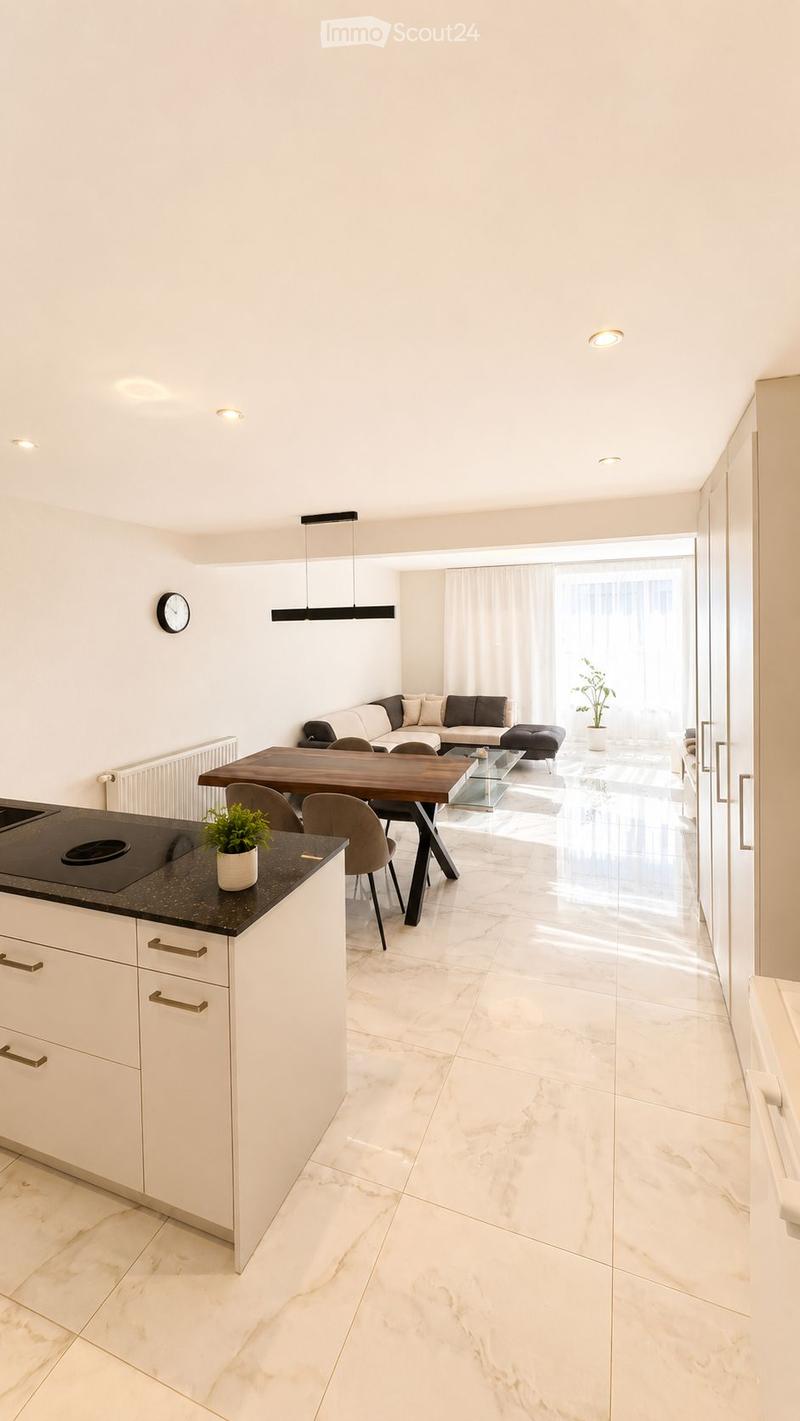 Modern open-plan living and dining area with white walls, marble flooring, and integrated kitchen. Features a sofa, coffee table, ottoman, dining table with chairs, and a kitchen island with a potted plant.