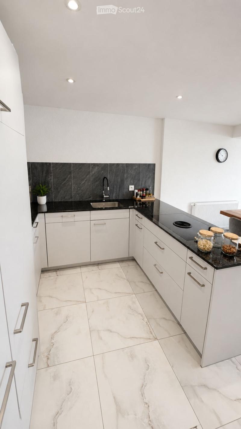 Modern kitchen with white cabinets, marble flooring, black countertop, sink, and small decorative jars on the counter.