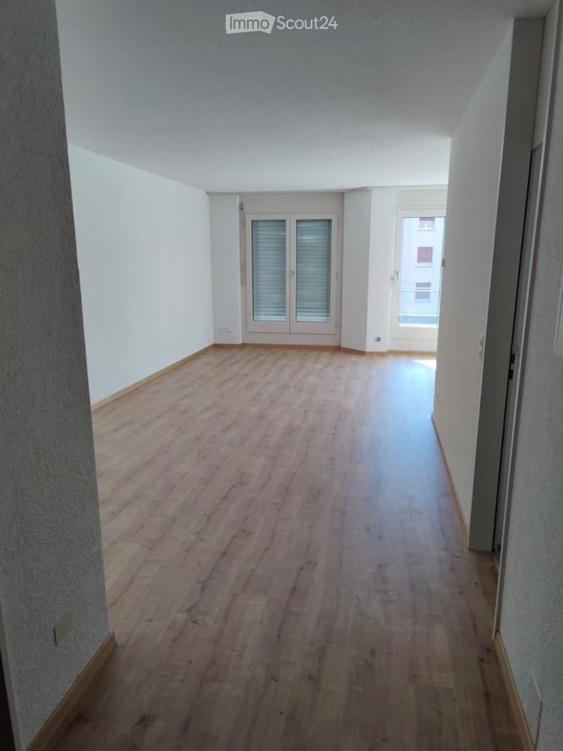 Empty hallway with wooden flooring, white walls, and two doors leading to other rooms.