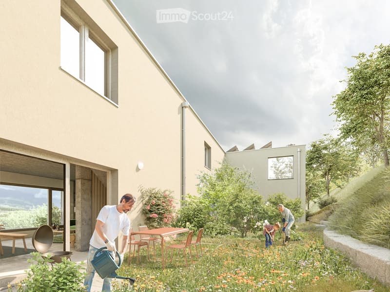 Garden area with a modern house in the background, featuring a table and chairs, lush greenery, and a person watering plants.
