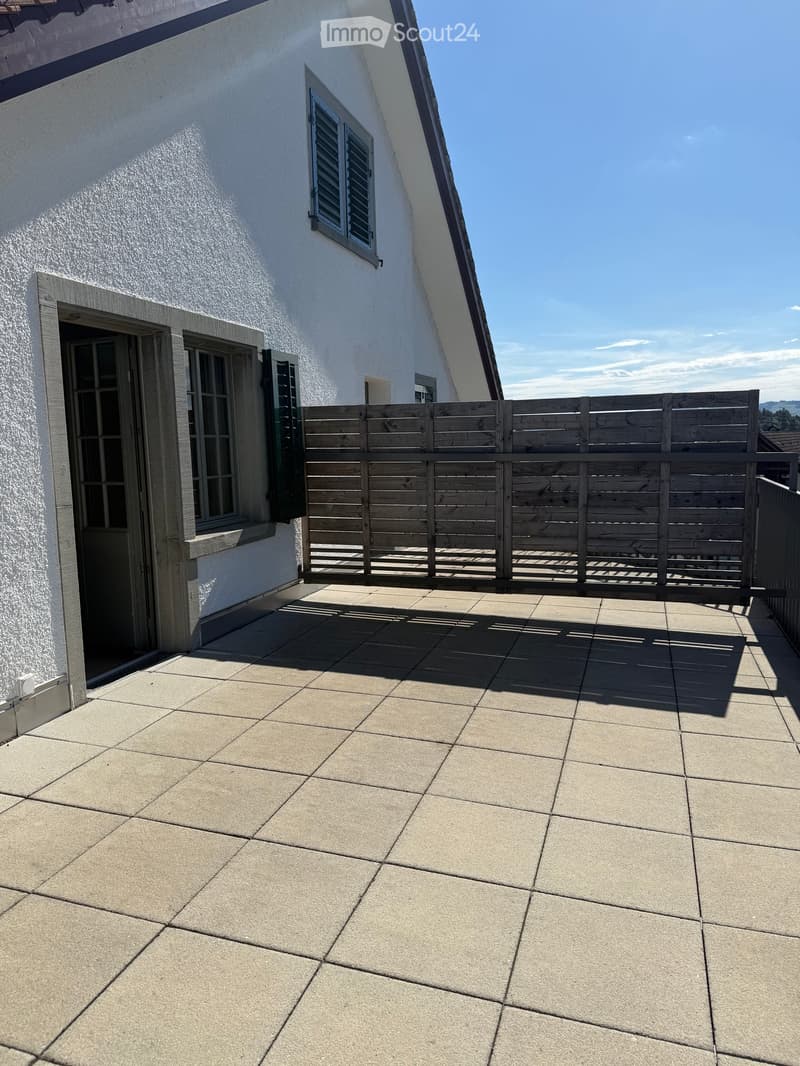 Balcony with tiled floor, wooden railing, and access to the building through a door.