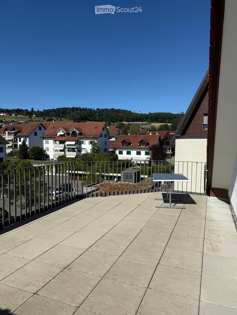 Balcony with concrete floor, metal railing, and a small table.