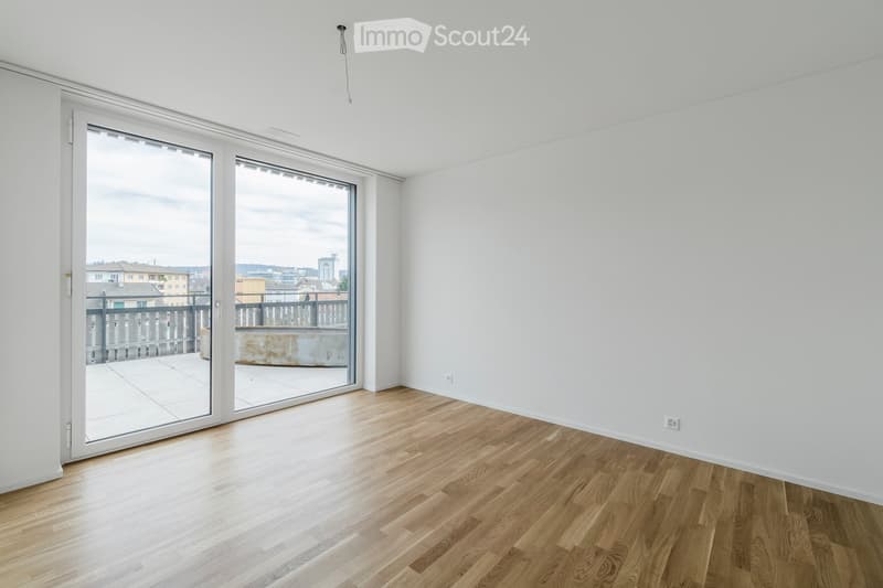 Empty room with wooden flooring, white walls, and large sliding glass doors leading to a balcony.