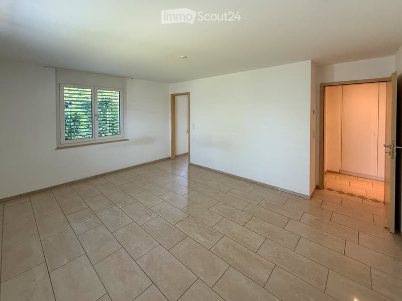 Empty room with tiled floor, white walls, and large windows with blinds. Two doors lead to adjacent spaces.