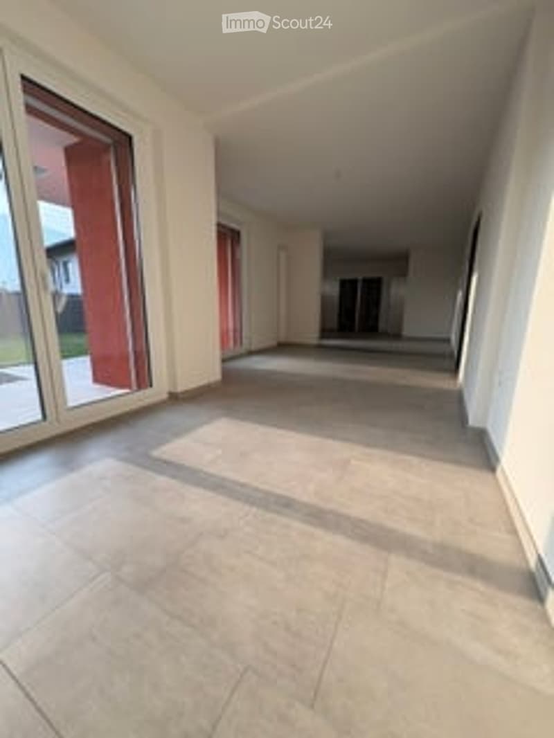 Empty hallway with large windows and tiled floor, no furniture or equipment.