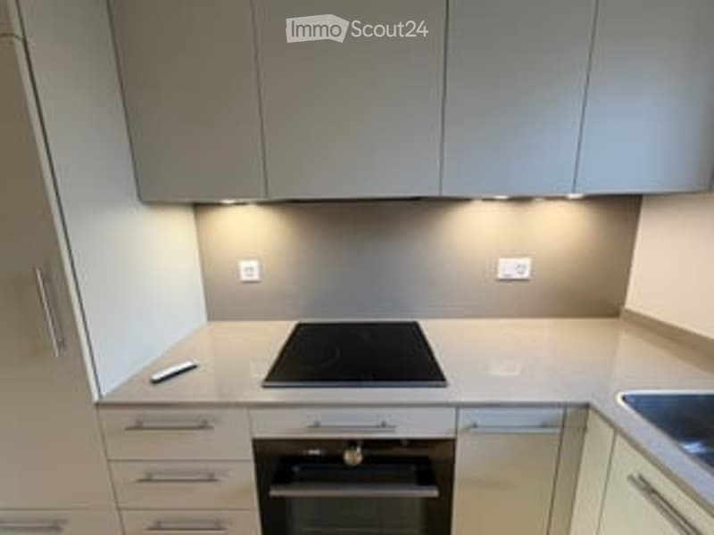 Modern kitchen with sleek, light-colored cabinets, an induction cooktop, and built-in oven. Minimalist design with clean lines and integrated lighting.