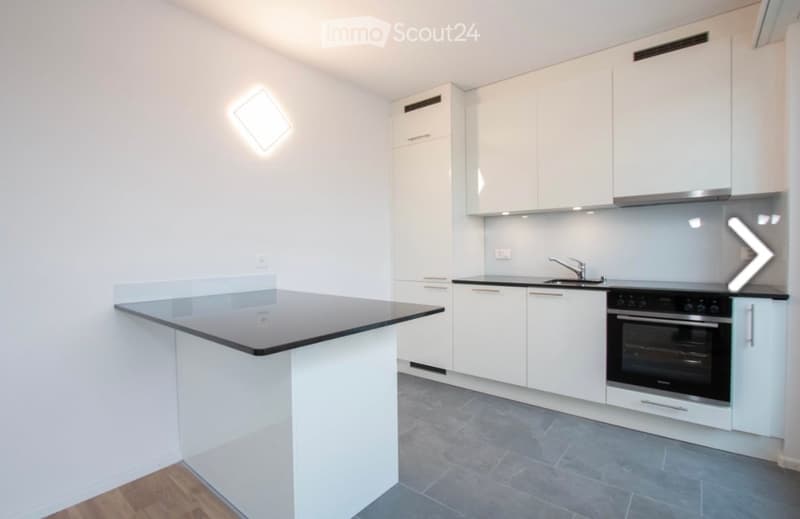 Modern kitchen with white cabinets, black countertop, sink, faucet, and built-in oven.