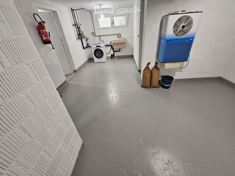Utility corridor with white brick walls, a washing machine, a sink, a fire extinguisher, and an air conditioning unit.
