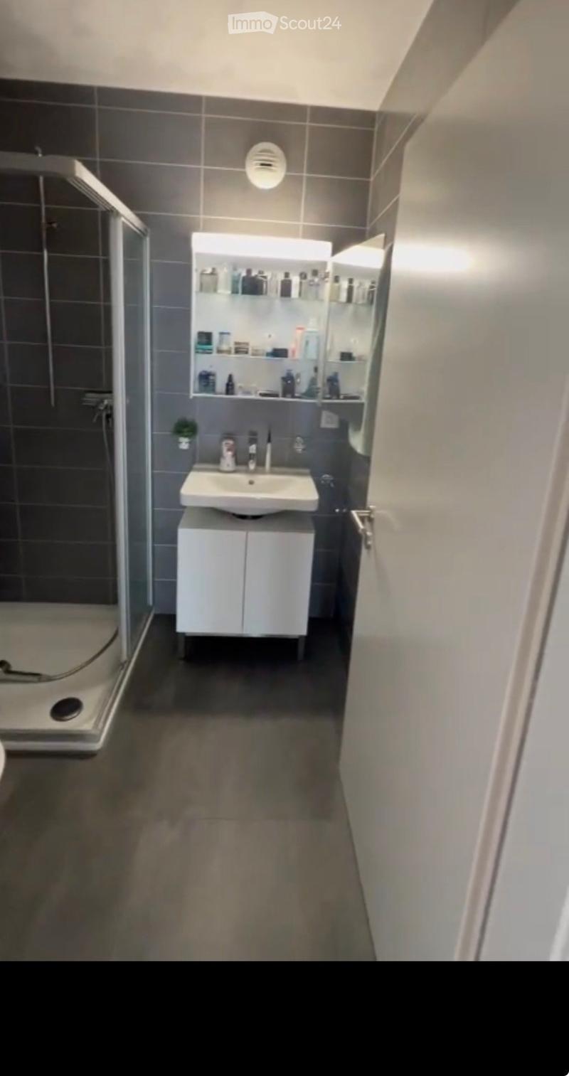 Modern bathroom with a white sink, mirrored cabinet, and a glass-enclosed shower area.
