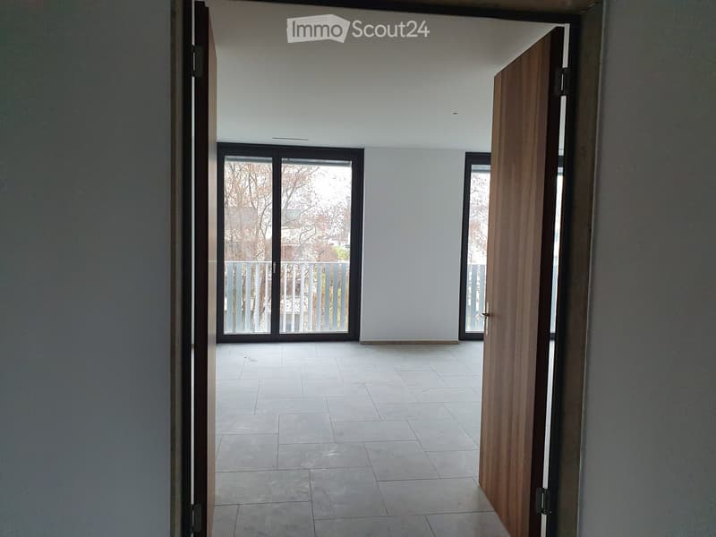 Empty hallway with tiled floor, white walls, and large sliding glass doors leading to an outdoor area.