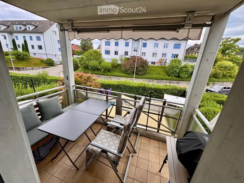Balcony with tiled floor, metal railing, and outdoor furniture including a table, chairs, and a sofa.