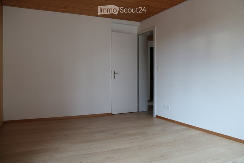 Empty room with light-colored walls, wooden flooring, and a closed white door leading to another space.