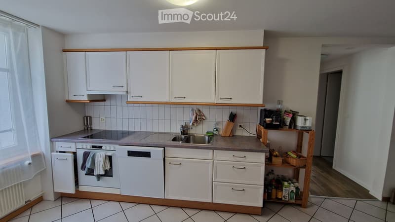 Modern kitchen with white cabinets, stainless steel appliances, and a wooden countertop. Includes an oven, dishwasher, sink, coffee maker, and various kitchen items.