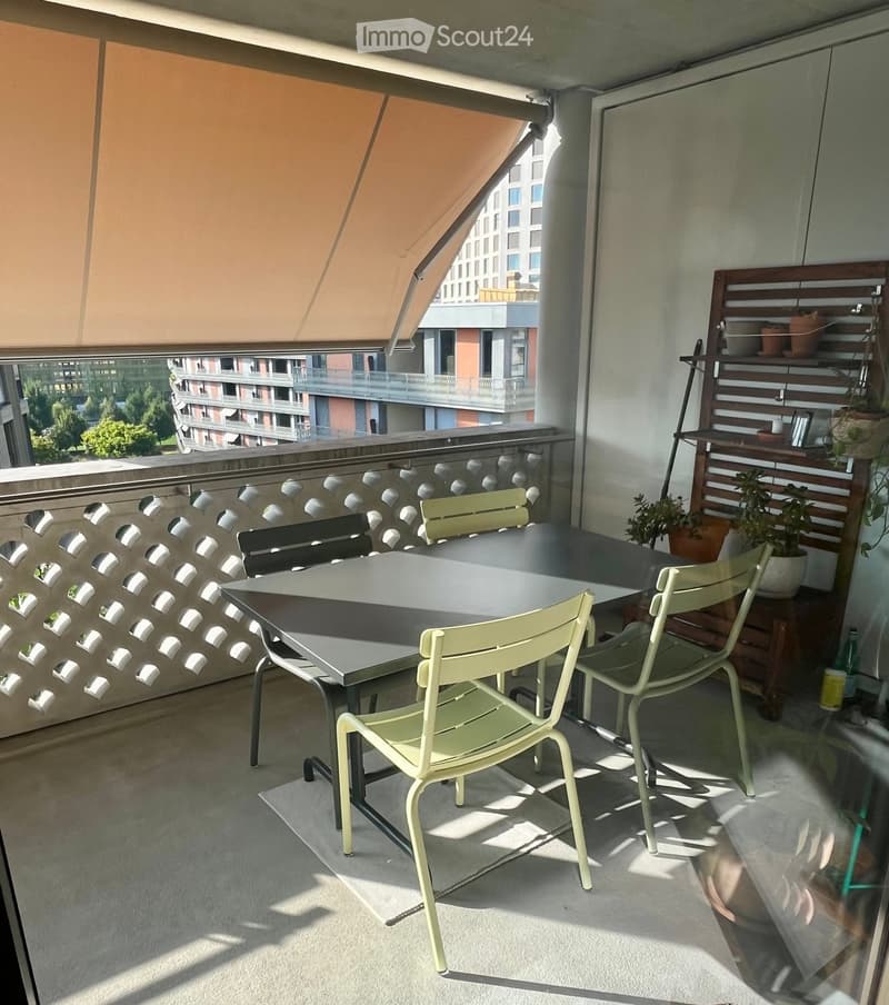 Balcony with a table, chairs, a shelf with potted plants, and a retractable awning.