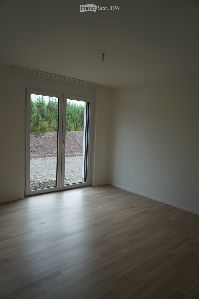 Empty room with wooden flooring and large sliding glass doors leading to an outdoor area.