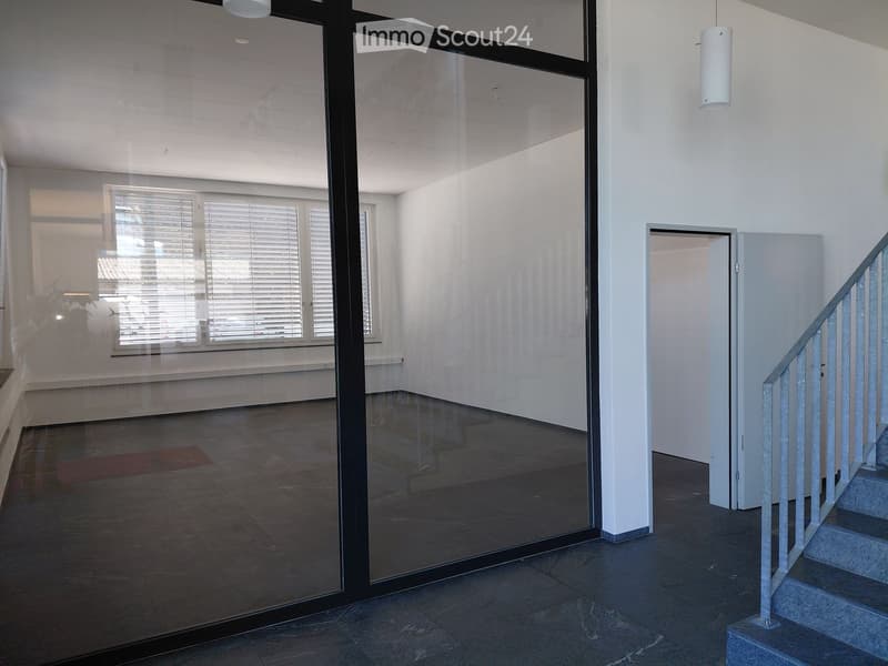 Bright, modern hallway with glass partitions, tiled floor, and a staircase leading upwards.