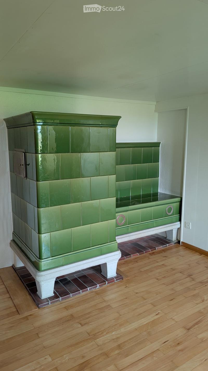 Green tiled bathtub with a built-in seat, placed on a wooden floor with a tiled base.