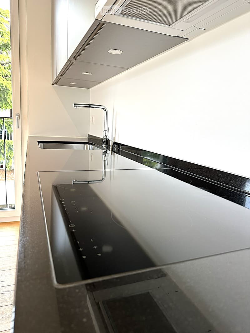 Kitchen. Modern kitchen with sleek black countertop, stainless steel sink, and minimalist faucet.