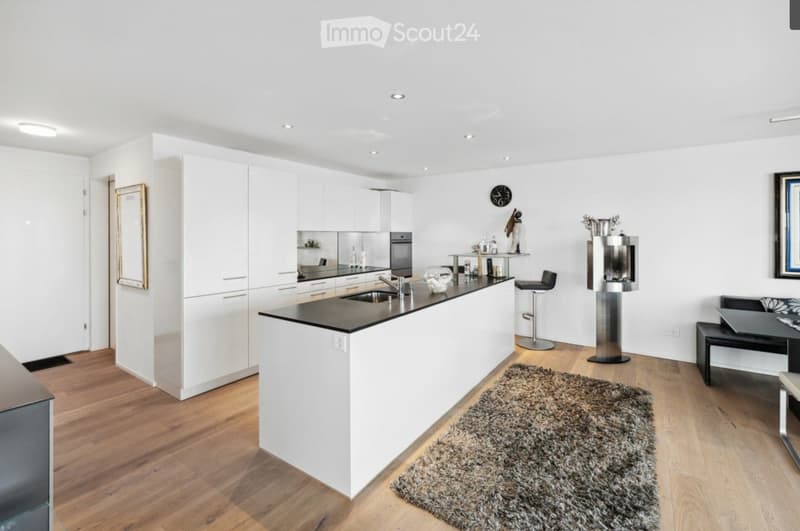 Modern kitchen with white cabinets, black countertop, island, sink, faucet, and a small seating area with a table and chairs.