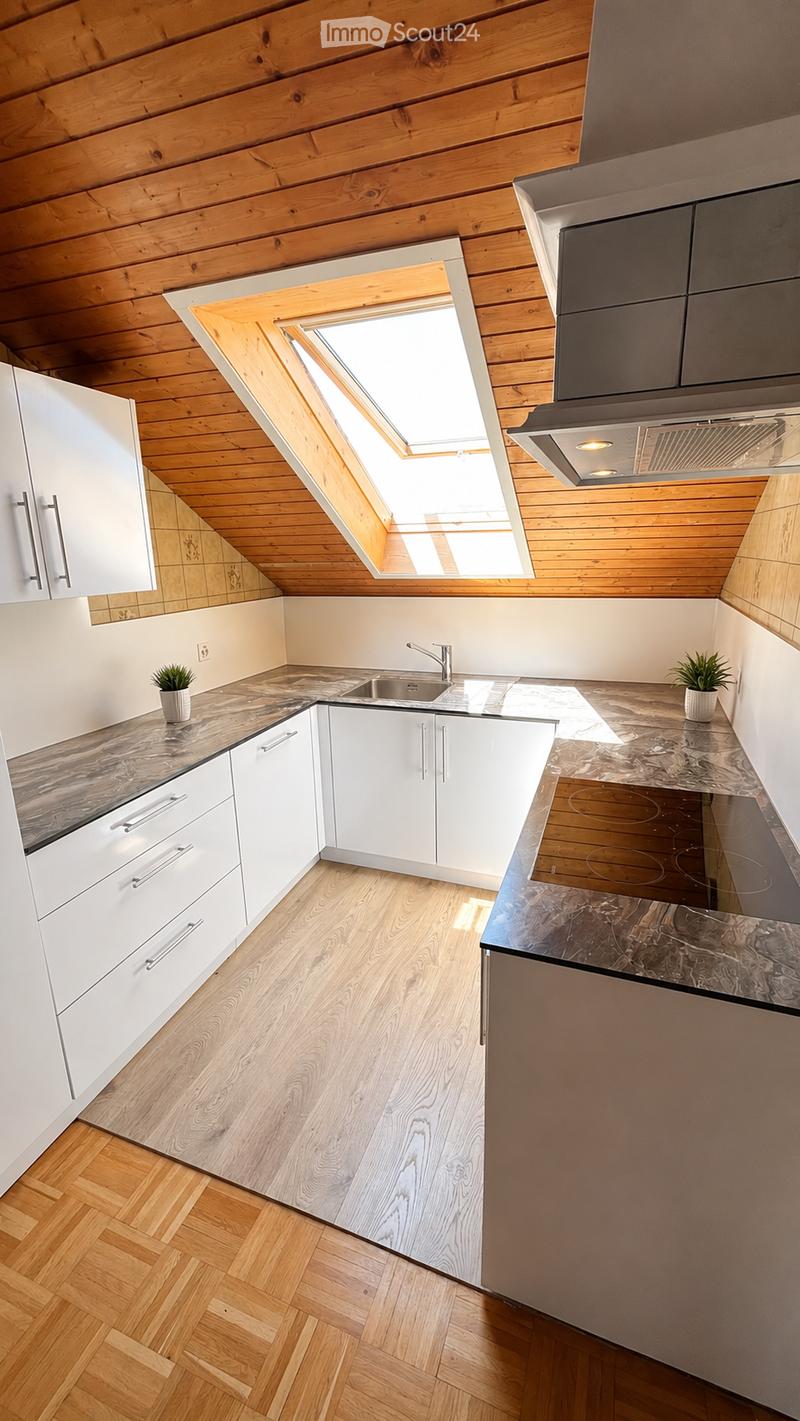 Modern kitchen with white cabinets, wooden flooring, marble countertops, and a skylight window above the sink.