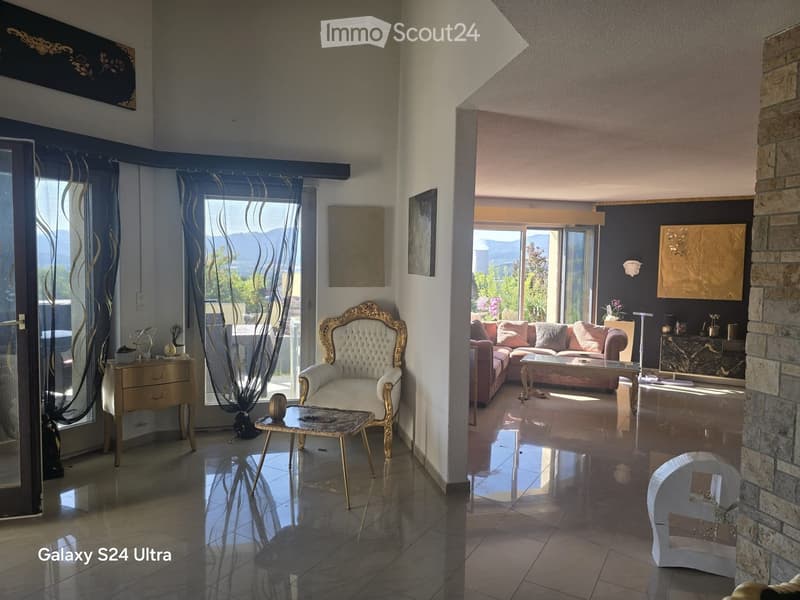 Elegant living room with a mix of modern and classic decor, featuring a tufted chair, sofa, coffee table, and decorative art pieces.