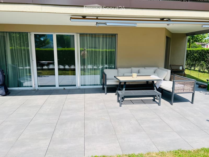 Balcony with tiled floor, large sliding glass doors, white sofa, small table, and bench.