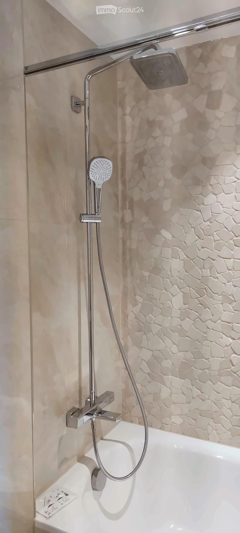 Modern bathroom with a bathtub, handheld showerhead, and a sleek chrome faucet.