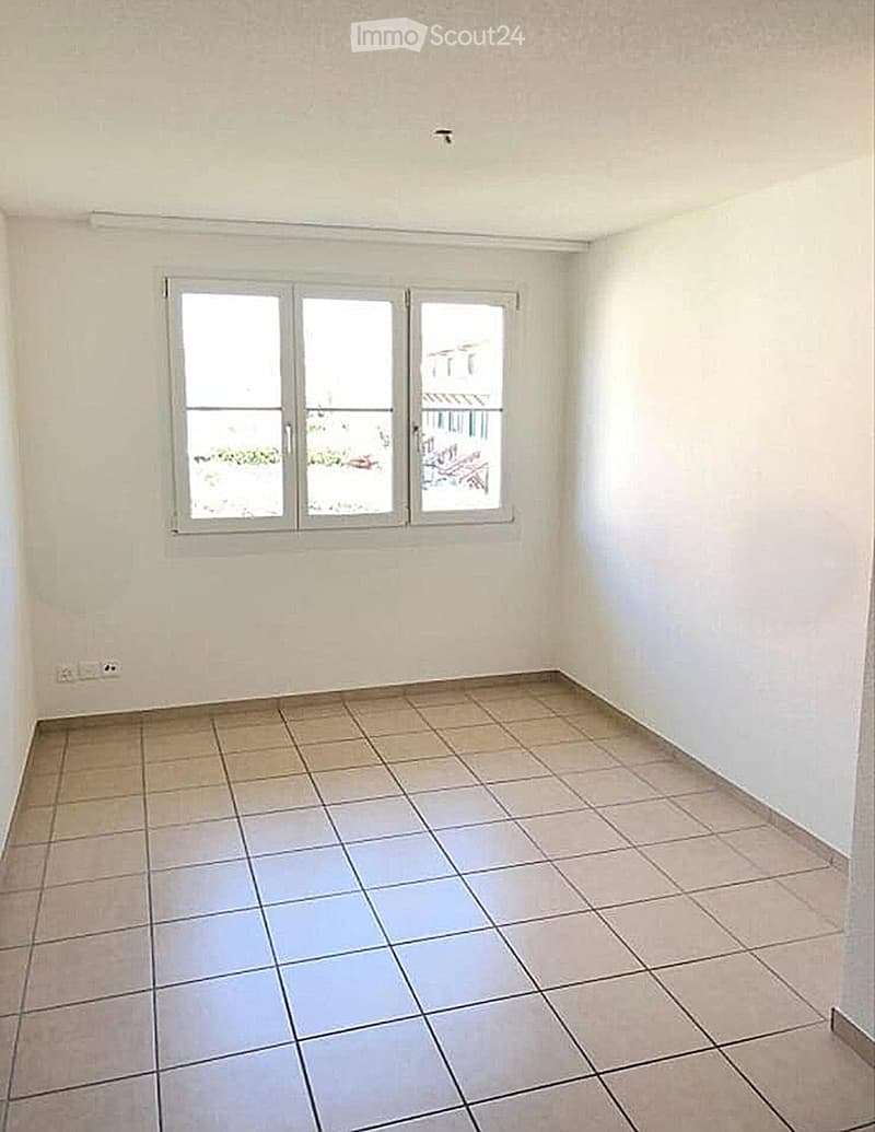 Empty room with tiled floor and large windows offering a view of the balcony area.